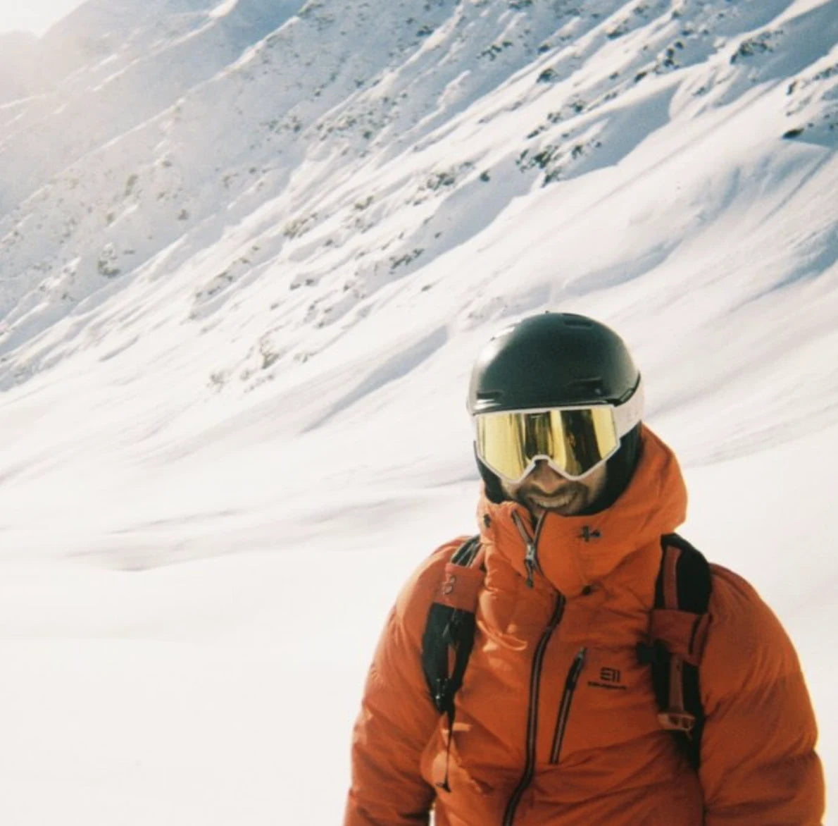 Sportif en veste orange dans la neige